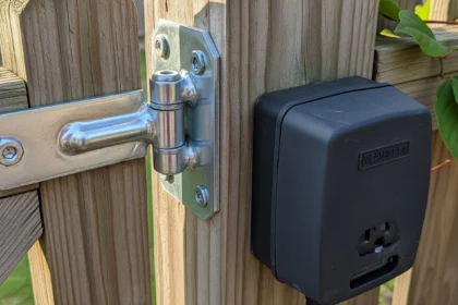 Repaired metal gate hinge and covered outdoor outlet for safer backyard use.