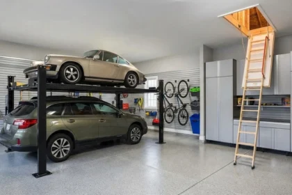 Organized residential garage with vertical storage, a car lift, and attic stairs